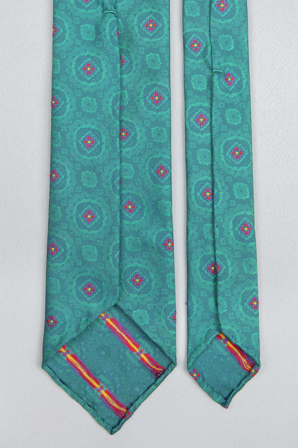 Cravate sartoriale à 7 plis retournée, le roulotté main permet de voir les fils du tissage Jacquard constituant les dessins du modèle.