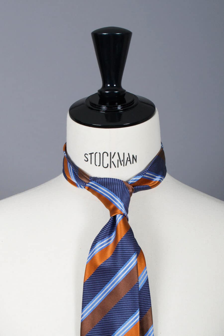 Cravate sartoriale à 7 plis, en soie tissée Jacquard, rayée orange et aperçu du noeud simple sur buste Stockman.