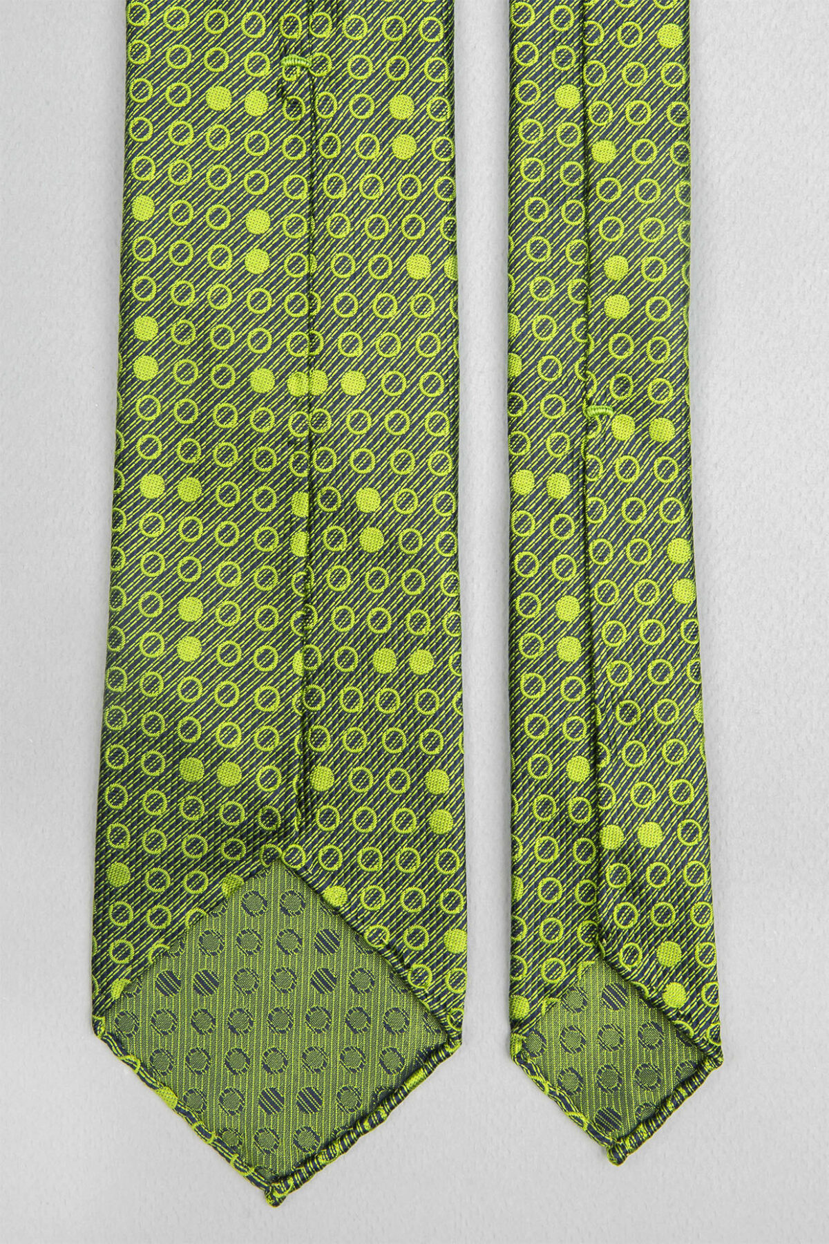 Cravate sartoriale à 7 plis retournée, le roulotté main permet de voir les fils du tissage Jacquard constituant les dessins du modèle.