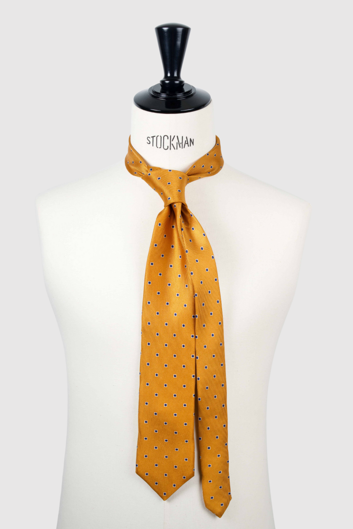 Cravate sartoriale à 3 plis, en soie tissée Jacquard, orange motif géométrique bleu marine et aperçu du noeud simple sur buste Stockman.