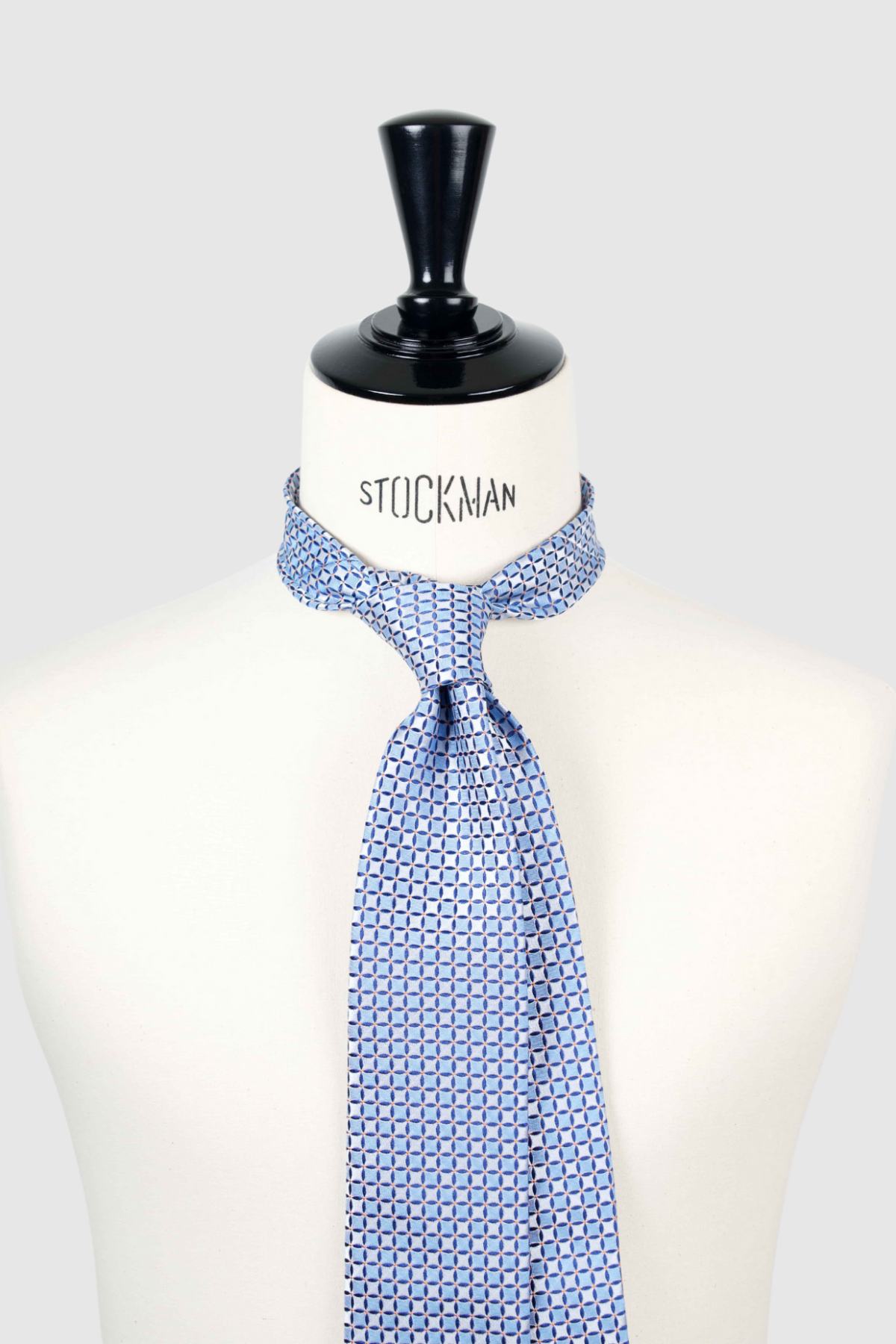 Cravate sartoriale à 3 plis, en soie tissée Jacquard, bleu ciel, motif géométrique et aperçu du noeud simple sur buste Stockman.
