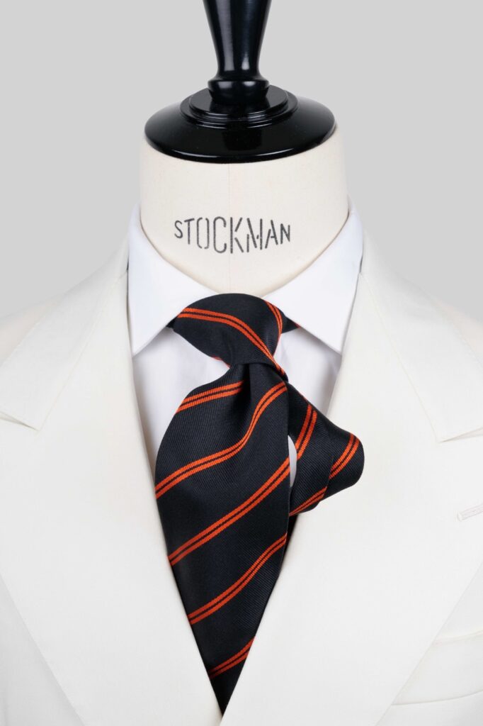 Regimental tie, navy with orange stripes, three fold, close-up view of the knot, Dare in Paris