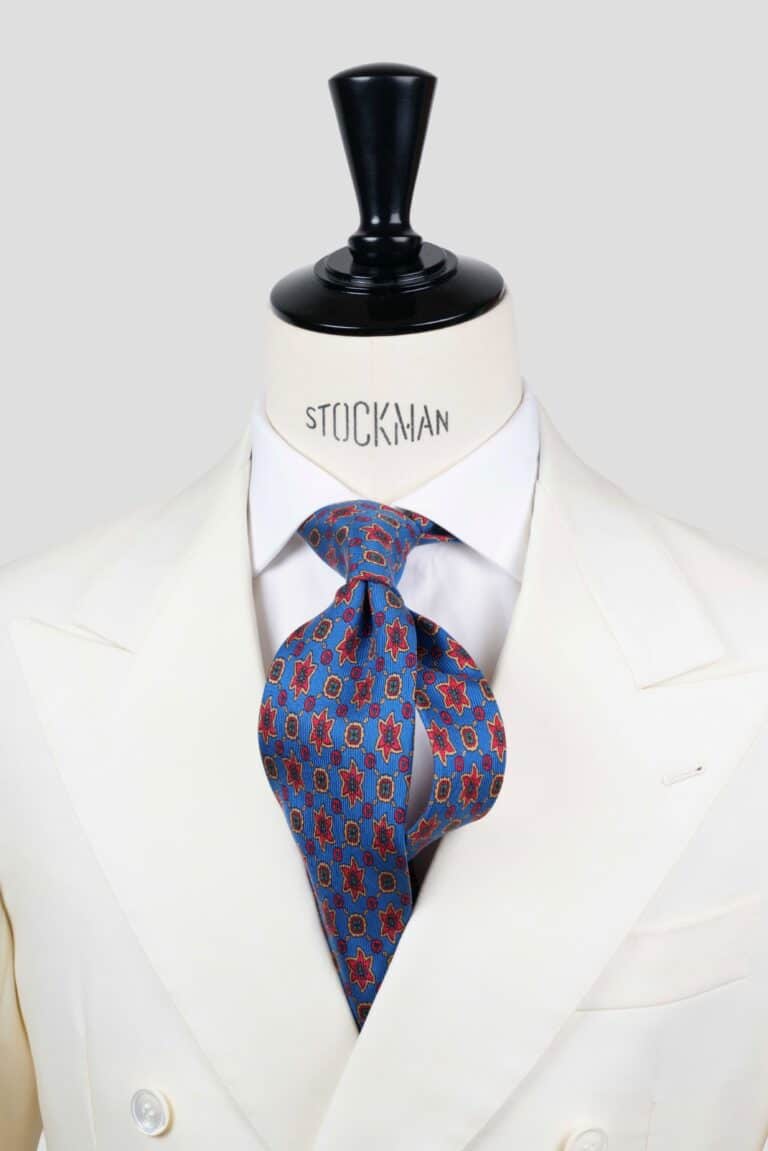 Cravate bleue à motif géométrique rouge et jaune, soie imprimée ancient madder 3 plis artisanale, nouée sur un buste, chemise blanche, Dare in Paris