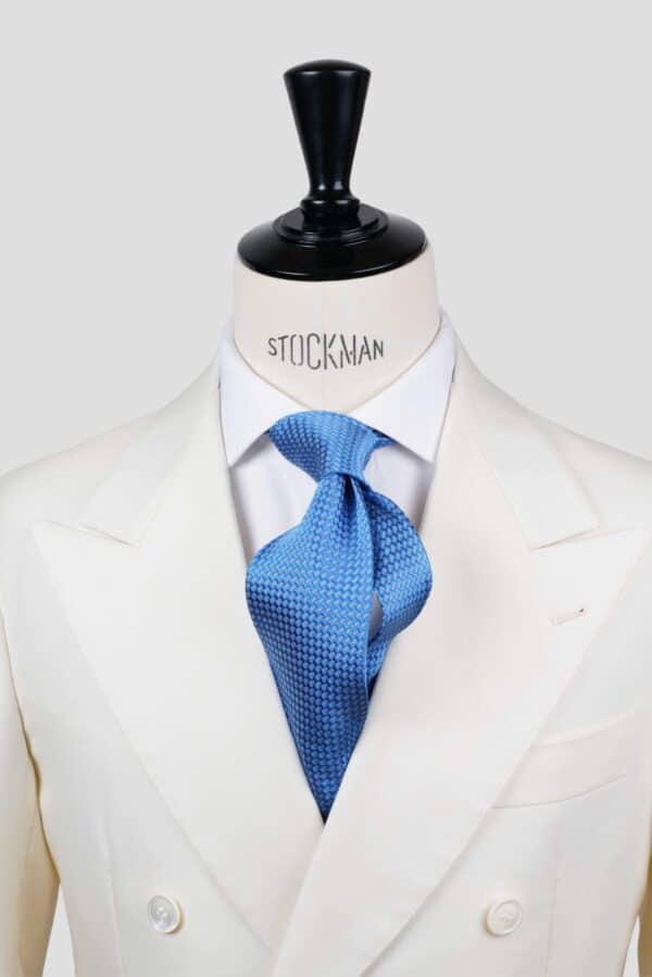 Cravate bleu ciel à motif blanc, soie tissée 3 plis artisanale, nouée sur un buste, chemise blanche, Dare in Paris
