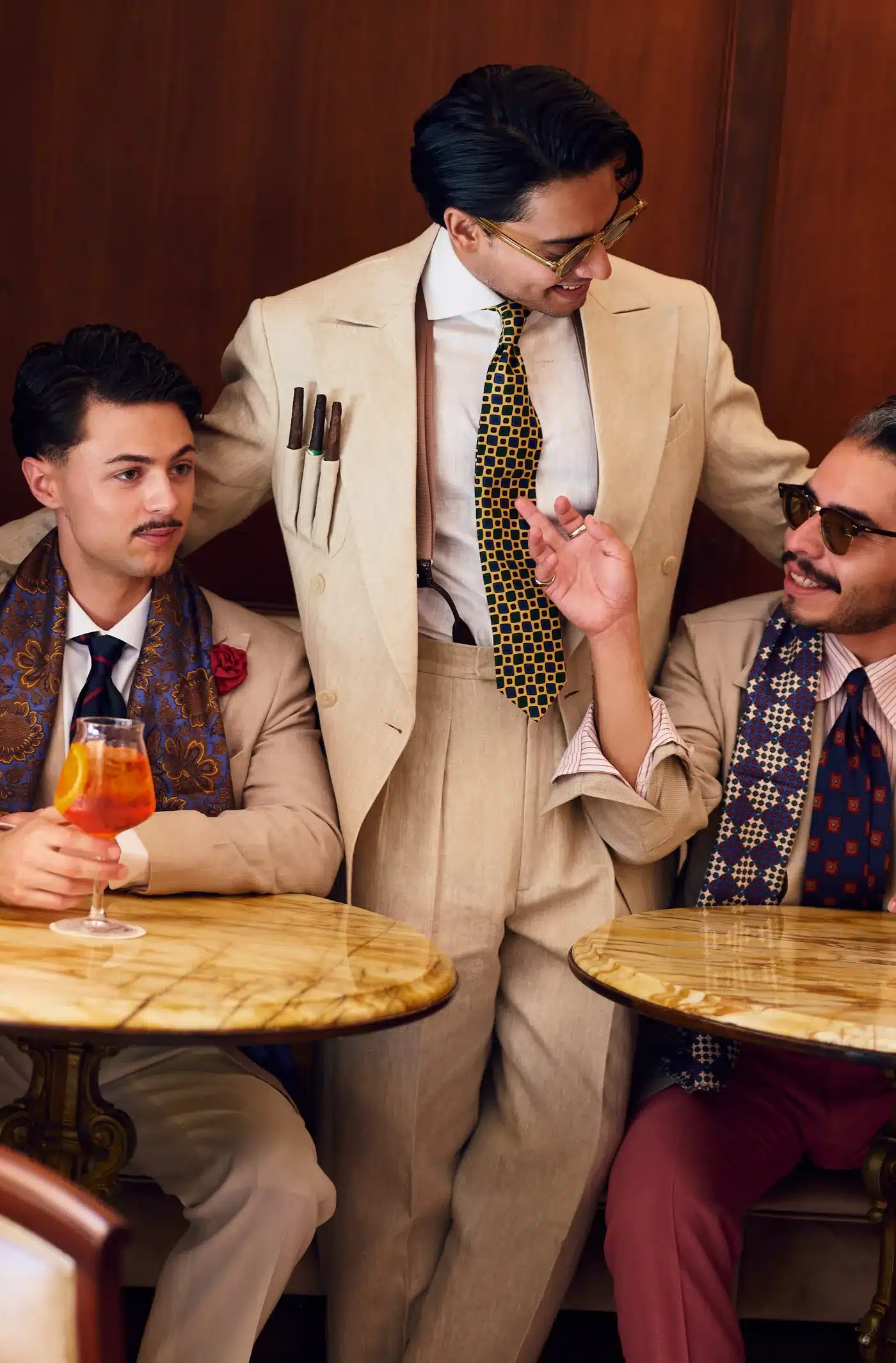 Trois hommes en costume crème portant des cravates et écharpes en soie Dare in Paris, café florentin