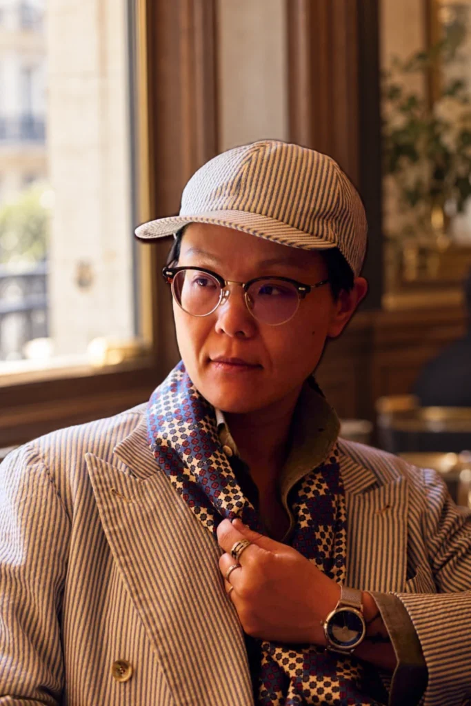 Midnight blue paisley tubular silk scarf, worn beneath a jacket by a man wearing a cap.