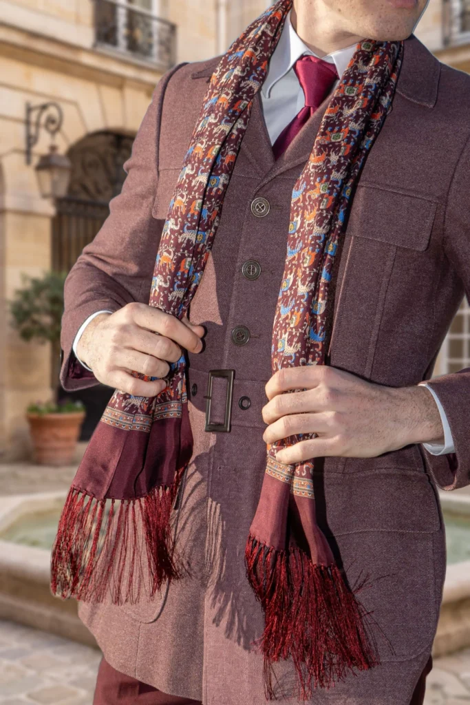 Foulard en soie bordeaux, motif éléphants, drapé autour du cou par un homme.