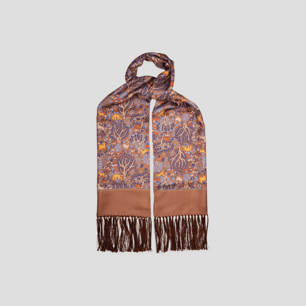 Foulard en soie camel, motif arbre de vie, présenté noué sur fond gris clair, avec ses franges.