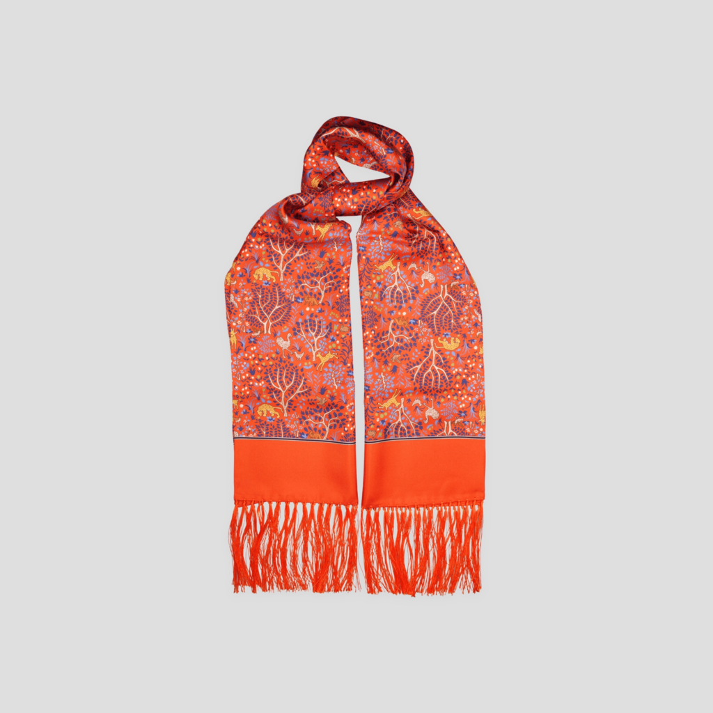 Orange silk scarf with Tree of Life pattern, shown loosely knotted against a light grey background, including its fringes.
