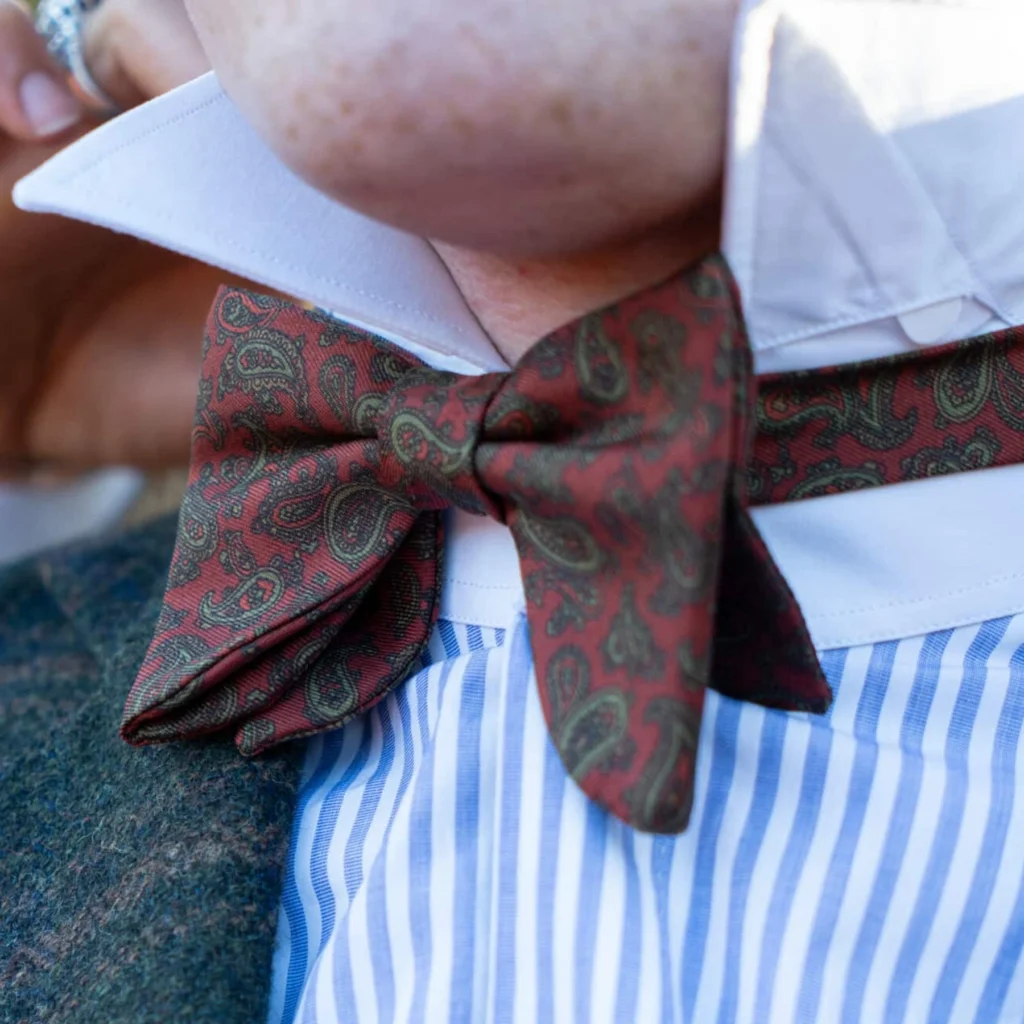 Nœud papillon orange soie imprimée, détail recadré du motif et du tissu de la vue portée.